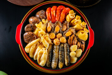 traditional giant hot pot Peng cai with dry seafood abalone sea cucumber crab prawn meat scallop oyster mushroom with thick brown sauce in red claypot asian Chinese new year luxury hotel menu