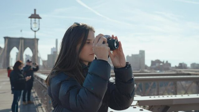 Cute woman taking a photo on a Brooklyn bridge, New York