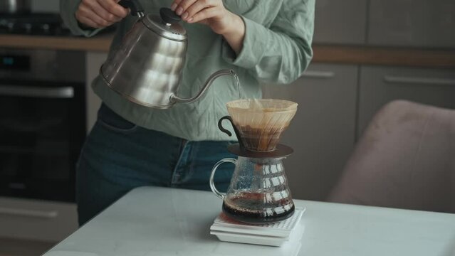Footage of woman brewing pour over coffee in kitchen, morning coffee ritual.