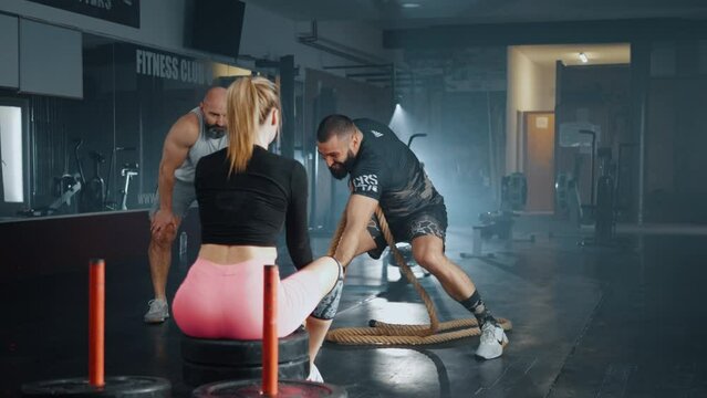 Strong cross fit training, young man pulling a sled with weights in the gym