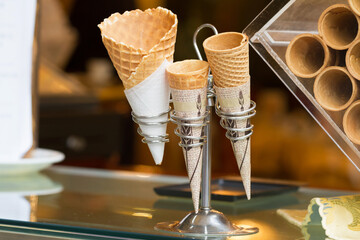 Set of empty wafer cones on the showcase in confectionery. Shop of sweets, candies and ice creams