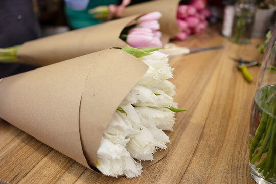 Bouquet of tulips in craft are on the florists desk in a flower shop. Flower delivery, orders are sent to the customer, mother's day, gifts, workplace, profession, manual labor, romance, date