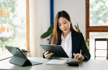  Beautiful Asian business woman typing laptop and tablet Placed at the table at the office..
