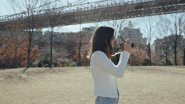 Cure girl taking a photo of Brooklyn bridge, New York