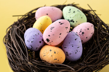 Naklejka na ściany i meble Colorful Easter eggs inside a nest on yellow background