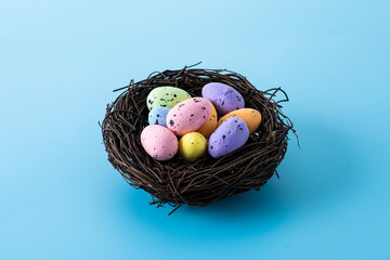 Colorful Easter eggs inside a nest on blue background