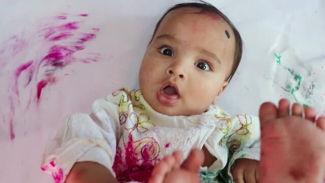 infant paying holi in traditional dress with colors from top angle