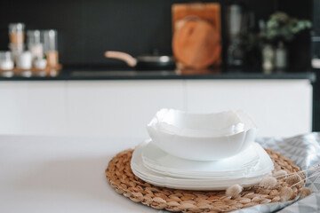 Set of white minimalist dishes on a table against the backdrop of a kitchen
