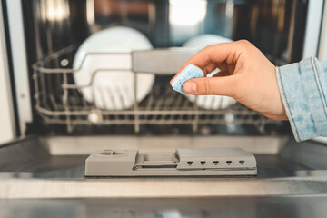 Dishwasher capsule, dishwasher tablets woman puts the capsule in the dishwasher