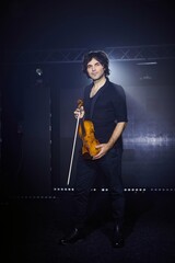 Violinist a player with a violin instrument in his hands. Artist of classical music or alternative music direction. Concept of stage art and performance.
