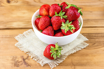 Top view of fresh strawberries in a plate on wooden background