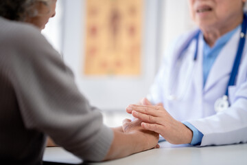 Obraz premium Male doctor holding hands to encourage senior patient and explai