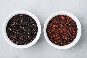 Fototapeta na wymiar Quinoa. Red black quinoa dry seeds in bowls on gray stone background, top view.