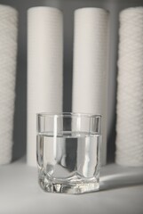 A glass of drink water and filter cartridges at white background