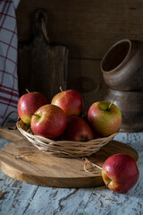 Red apples in a straw wicker plate on a wooden table