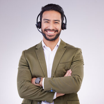 Call Center Employee, Man With Smile And Arms Crossed In Portrait, Headset With Mic, CRM And Contact Us. Communication, Customer Service Or Tech Support Mockup With Happy Male On Studio Background