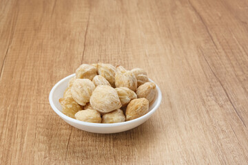 Kemiri or Candlenut Seeds on wooden background, food ingredient
