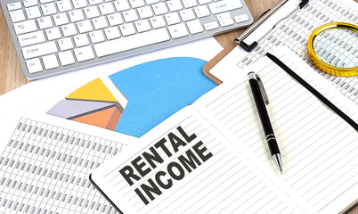 Fototapeta premium RENTAL INCOME text on notebook with chart and keyboard