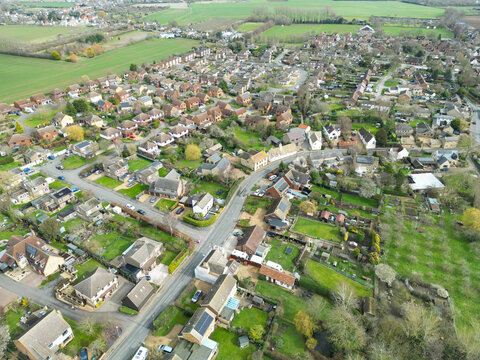 Drone view of a sprawling East Anglian village showing the main roadway leading through the bottom left of the image. An ancient orchard is on the lower right.