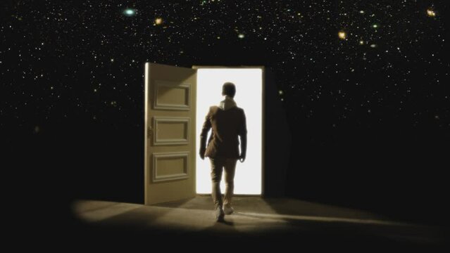Back , rear view of man walking in front of an open door with darkness behind . Footage of person walking on floor . White light inside the door. Concept of anonymous,  spirit in coma or teleportation