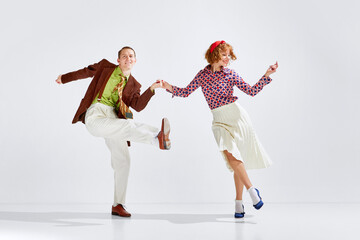 Feeling happy and positive. Young smiling man and woman in stylish clothes dancing retro dance...