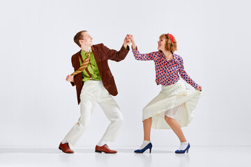 Showing positive energy. Young man and woman in stylish clothes dancing retro dance against grey...