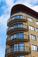 Fototapeta na wymiar Brick apartment building with retro rounded corner windows and balconys.