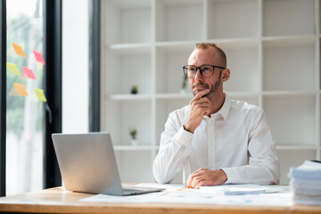 Obraz premium Image of young businessman analyzing work using a laptop at office