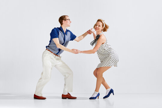 Young man and woman in stylish clothes dancing retro dance against grey studio background. Social dance club. Concept of art, retro style, hobby, party, fun, movements, 60s, 70s culture