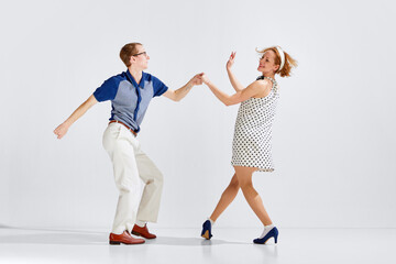 Young excited man and woman wearing stylish clothes dancing retro dance isolated on white...