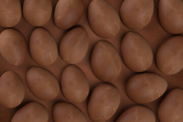 Delicious chocolate easter eggs on chocolate background. Concept Easter wallpaper.