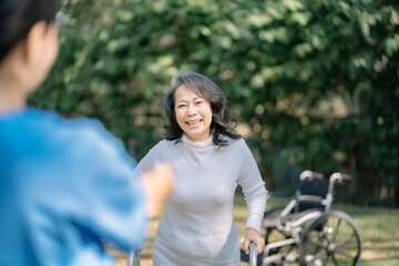 Smiling physiotherapist taking care of the happy senior patient in wheelchair, outdoor.
