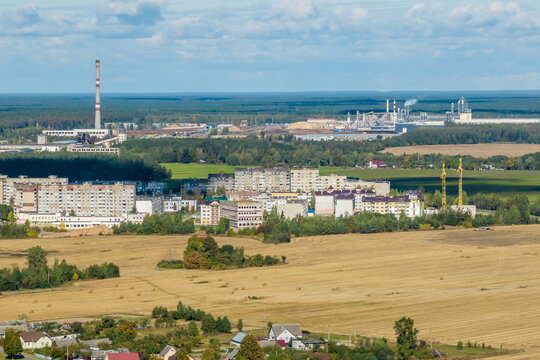 aerial panoramic view of city with a huge factory with smoking chimneys in the background