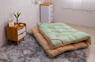 The orange and green colored mattress (Topper) was neatly folded up in the middle of the bedroom.
