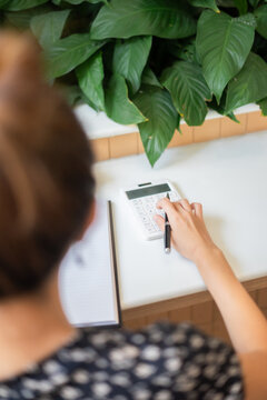 Above top close up back view working woman with note papers and calculator calculating financial in cafe. Women seller online note order on paper and calculate sales 