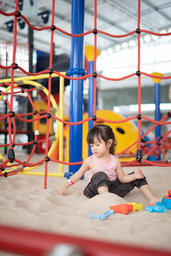 A little cute girl playing with sand at the playground outdoors. Creative learning activities for kids.