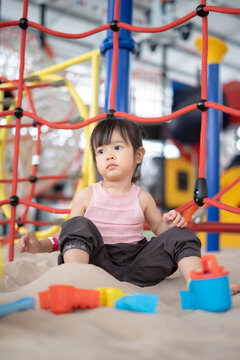 A little cute girl playing with sand at the playground outdoors. Creative learning activities for kids.