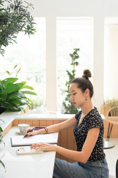 Woman work with financial note papers and using a calculator calculating financial at cafe. Women seller online note order on paper and calculate sales with favorite cup of coffee hot latte