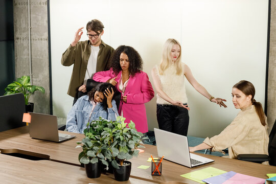 Frustrated Business People Sitting At The Table In Office, Arguing While Discussing Project. Their Female Colleague Covering Her Face With Hands Looking Exhausted And Ill. Business Problem Concept