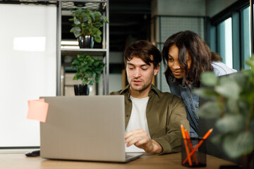 Software developer showing his colleague his work on a laptop