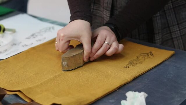 Hand-printed pattern on fabric. Women's hands put a seal on the shopping bag. Ancient traditions. Modern hobbies and creativity.