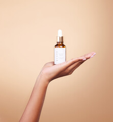Hand, product and antiaging serum with a woman in studio on a beige background to promote skincare....