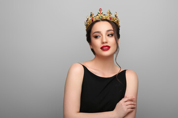 Beautiful young woman wearing luxurious crown on light grey background, space for text © New Africa
