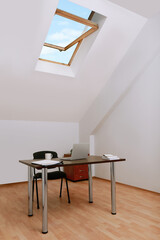 Stylish workplace with laptop and documents in attic room. Interior design