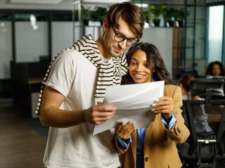 Young African American ethnic business woman with a partner in the office joyfully look at the documents
