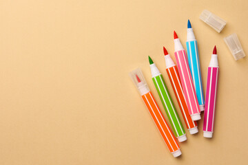 Many bright markers on beige background, flat lay. Space for text