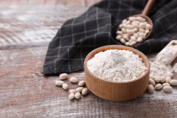 Fototapeta na wymiar Bean flour and seeds on wooden table. Space for text