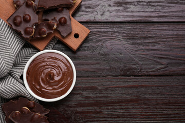 Bowl with tasty paste and pieces of chocolate on wooden table, flat lay. Space for text