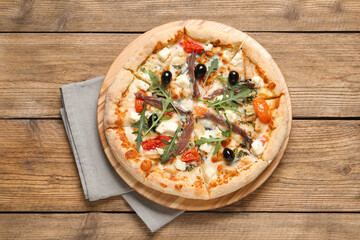 Tasty pizza with anchovies, arugula and olives on wooden table, top view