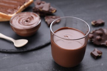 Tasty homemade paste and pieces of chocolate on black textured table, closeup